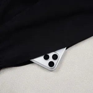 Detail of deep pocket on black loose silhouette trousers holding a white smartphone