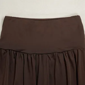 Close-up view showing the waistband and pleated fabric detail on dark brown wide-leg pants