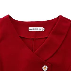 Close-up of red V-neck short-sleeved top with brand label and white daisy button