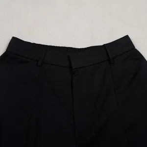 Detailed close-up of the elastic waistband and front fly of black commute trousers.