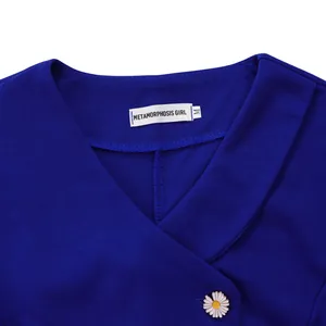 Close-up detail of a royal blue blouse neckline with a white brand label and a daisy