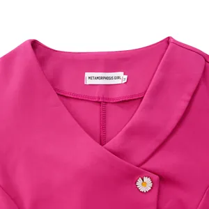 Detailed macro view of magenta V-neck top featuring a white daisy button and neck label.
