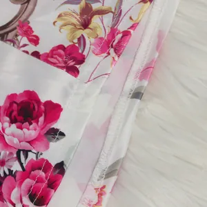 Macro detail showing pink floral print fabric and neat hem stitching on a white fur rug.