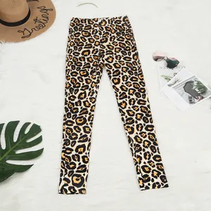 Flat lay of leopard print leggings on white fur rug with tropical summer accessories.