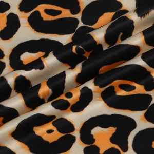 Close-up view of vibrant leopard print fabric showing smooth and glossy satin texture.
