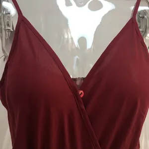 Detail shot of the V-neck and delicate button on this elegant red strappy jumpsuit.