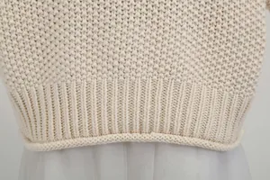 Detailed close-up view of a cream chunky knit sweater with ribbed hemline finish