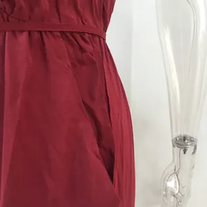 Detailed close-up of a burgundy jumpsuit featuring side pocket and waist tie-strap