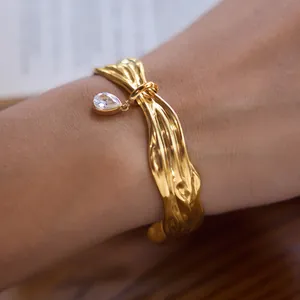Λεπτομερής προβολή επίχρυσου βραχιολιού 18k με κρεμαστό ζιργκόν σε σχήμα δάκρυ