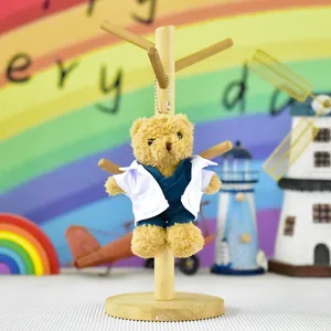 Detailed view of plush teddy bear wearing miniature doctor white coat and blue scrubs.