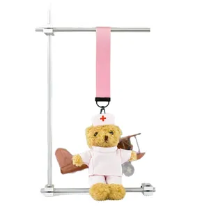 Adorable plush teddy bear dressed in pink nurse uniform hanging on a metal stand