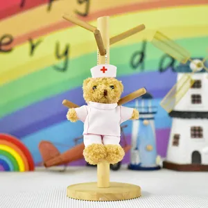 Cute nurse teddy bear plush doll in pink outfit on a wooden stand with rainbow background