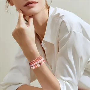 Detail view of stacked rose quartz and pink natural stone beaded bracelets on wrist