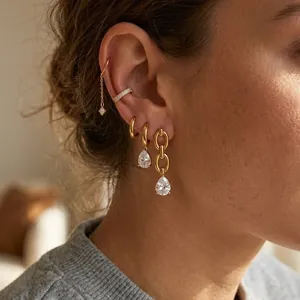 Detail showing elegant gold titanium steel earrings with pear-shaped zircon drops