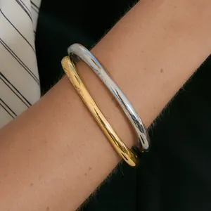 Close-up detail of minimalist stainless steel bangles in polished gold and silver finishes