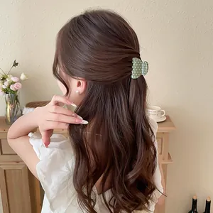 Detailed view of an elegant green polka dot acrylic hair claw clip on long wavy hair.