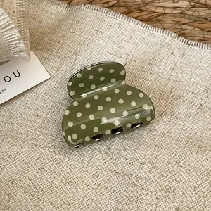 Detailed view of olive green acrylic hair claw clip with white polka dots.