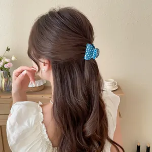 Detail view showing blue polka dot bow hair claw clip on brunette wavy hair styling