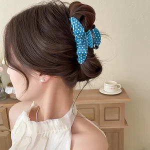 Detail shot of a blue polka dot bow hair claw clip styled in a classic messy bun look