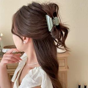 Elegant green polka dot acrylic hair claw clip used for a half-up bun hairstyle
