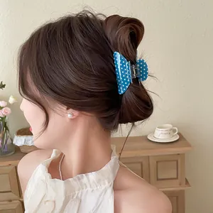 Close-up view of a blue polka dot butterfly hair claw clip styled in a classic chic bun