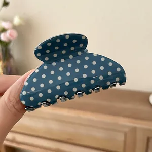 Macro view of an elegant blue acrylic hair claw clip featuring a white polka dot pattern