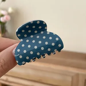 Close-up of a blue acrylic hair claw clip with white polka dots for elegant styling