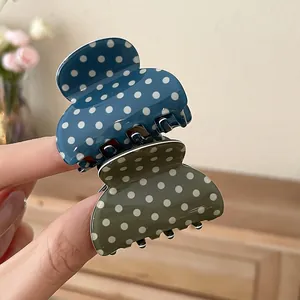 Detailed view of polka dot pattern acrylic hair claw clips in blue and olive green colors