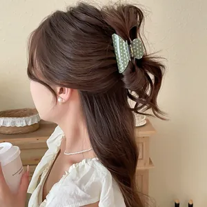 Close-up of green polka dot acrylic hair claw clip used for a half-up bun hairstyle