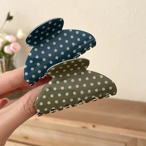 Close-up of blue and olive green polka dot acrylic hair claw clips for women.