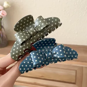Close-up of elegant polka dot bow acrylic hair claw clips in olive and blue tones