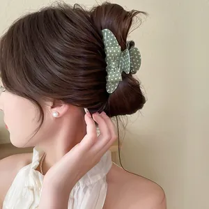 Detail of a green polka dot bow hair claw clip on an elegant and sophisticated updo