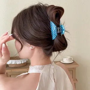 Detail showing a blue polka dot butterfly hair claw clip on a woman's hair bun