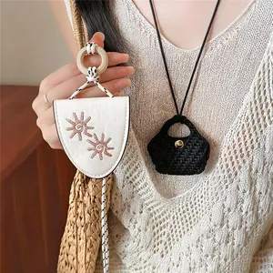 Close-up of chic vintage leather eyeglass holder necklaces on a cream knit sweater