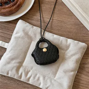 Macro view of black woven leather pouch pendant necklace featuring a gold button accent