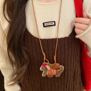 Close-up of cute flocked dog glasses holder necklace worn on a brown knit vest