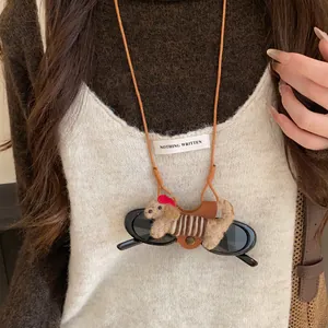 Close-up detail of cute flocked puppy glasses holder necklace on brown leather cord