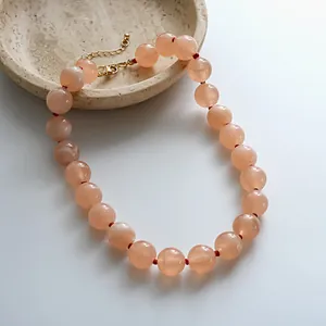 Collier de perles en acrylique pêche ajustable avec accents rouges, style minimaliste.
