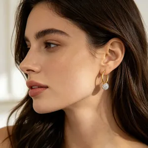 Elegant gold stainless steel hoop earrings featuring a sparkling pavé ball charm shown on model
