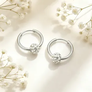 Close-up of silver stainless steel hoop earrings with a sparkling crystal ball charm.