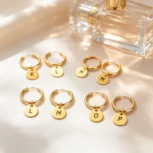 Close-up view of gold stainless steel hoop earrings featuring engraved letter charms