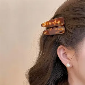 Detailweergave van schildpad-acryl haarclips op bruin golvend haar