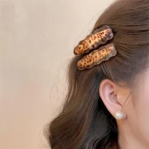 Detailopname van model met stijlvolle acryl haarspeldjes met golvende luipaardprint