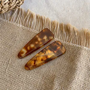 Detailweergave van twee vintage acryl haarclips met luipaardprint op jute stof