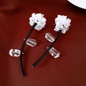 Close-up detail of unique crystal flower earrings featuring black leather cord stems