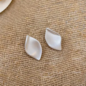 Détail en gros plan de la texture brossée mate de ces boucles d'oreilles en forme de feuille