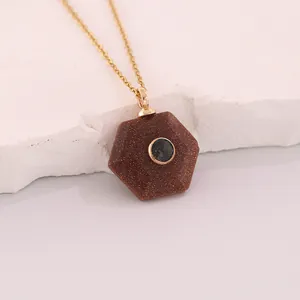 Macro detail of a hexagonal brown goldstone pendant with blue inlay on gold chain