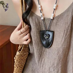 Elegant polka dot heart pendant necklace with pearl chain shown on a model outfit