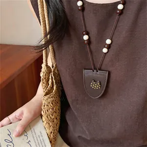 Detailed close-up of a long brown beaded sweater chain with cat motif pendant
