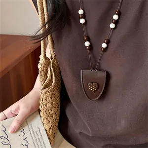 Detail of a Korean style brown leather heart pendant necklace with beads worn by a model